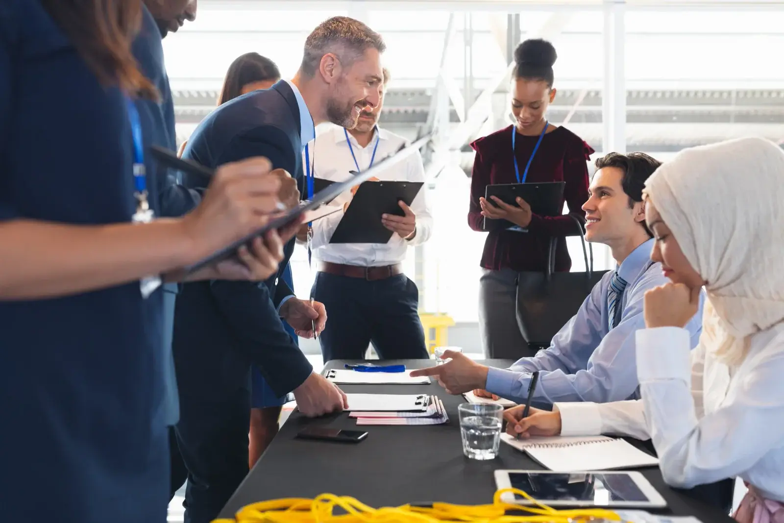 Staff with clipboards and lanyards help attendees signing in at a registration table